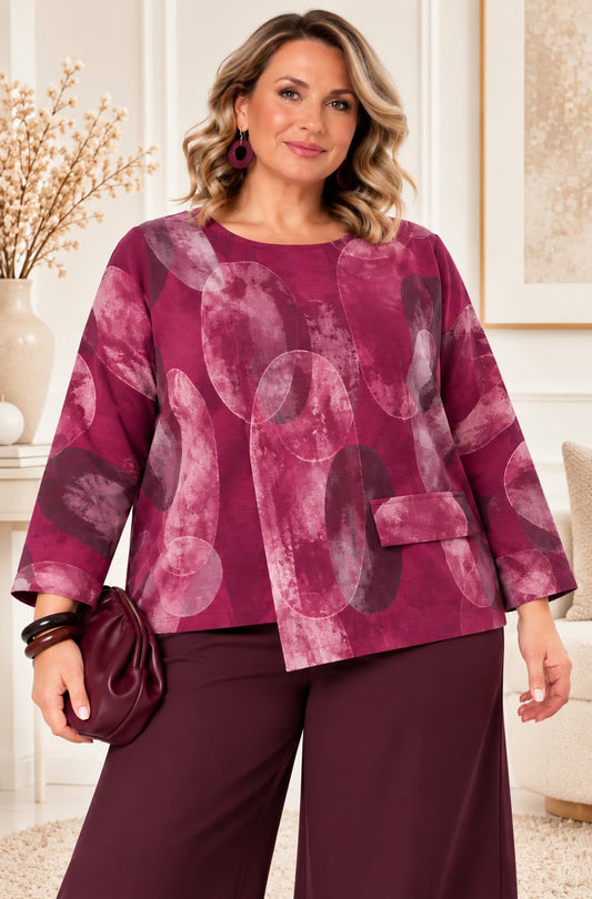 Vue de face du top ample à motif abstrait en coloris fuchsia et rose, avec encolure ronde, manches trois-quarts et panneau asymétrique devant.