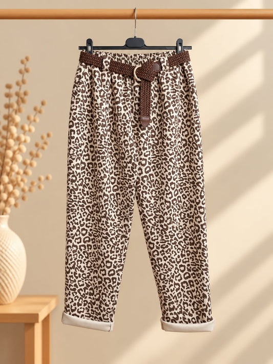 Vue de face sur cintre du pantalon Animal à imprimé léopard clair et brun, avec ceinture tressée marron à boucle arrondie, plis devant et revers clairs au bas des jambes.